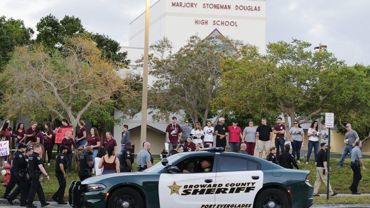 In this Feb. 28, 2018, photo, a police car drives by Marjory Stoneman Douglas High School in Parkland as students return to class for the first time since a former student opened fire there with an assault weapon.