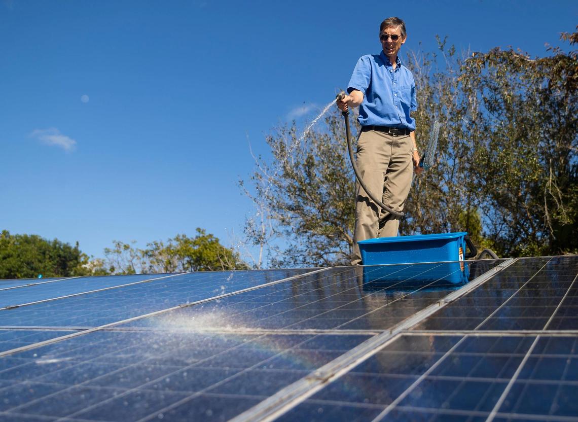 Phil Stoddard, chair of the Green Corridor, cleans the solar panels on his roof on Wednesday, Jan. 31, 2023, in South Miami, Florida.