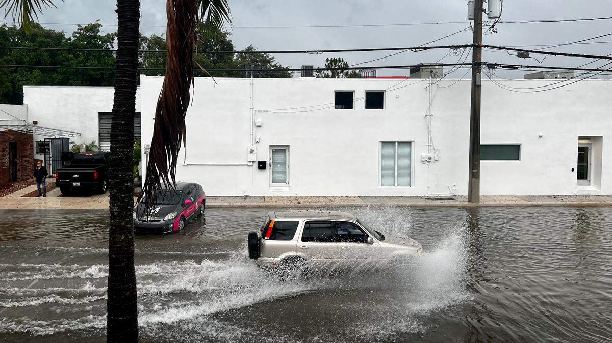 A car passes through a flooded street in the Little Haiti neighborhood of Miami, Florida, on Tuesday, June 6, 2023.