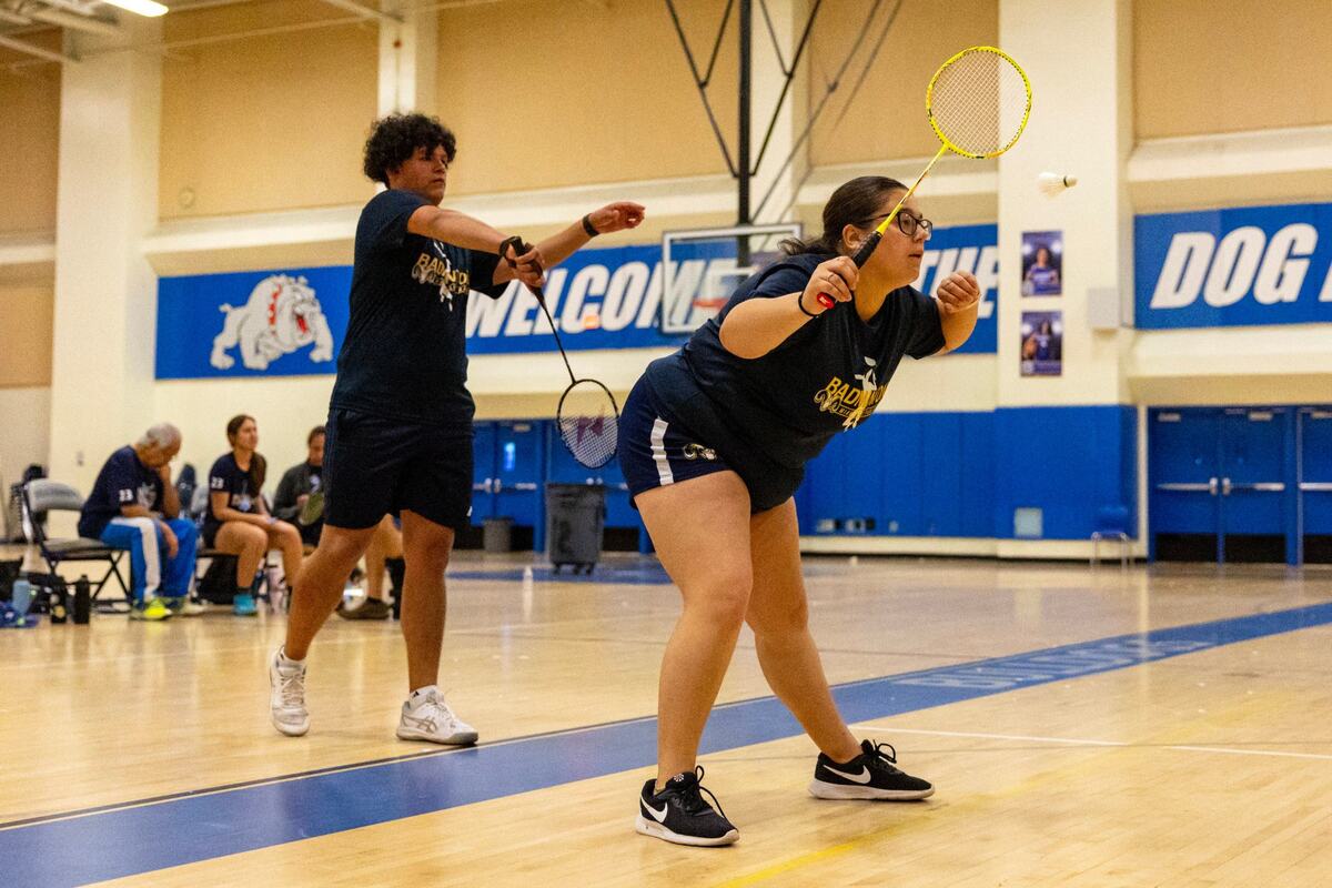 Sebastian Mota, 17, left, serves the shuttle as Madelyn Casco, 17, right, looks on during the GMAC badminton final for mixed doubles at Braddock High School in Miami, Florida, on Thursday, April 18, 2024.
