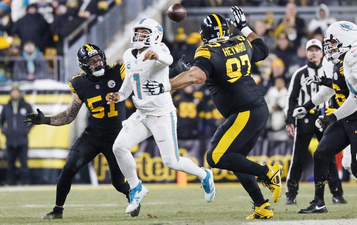 Miami Dolphins quarterback Tua Tagovailoa (1) passes the ball on the run as Pittsburgh Steelers linebacker Nick Herbig (51) and defensive tackle Cameron Heyward (97) give chase during the first half of their NFL football game at Acrisure Stadium in Pittsburgh, PA., on Monday, December 15, 2025. 