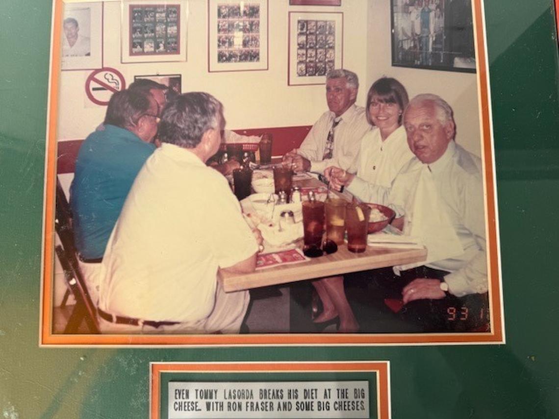 Tommy Lasorda (bottom right) at a table with UM baseball coach Ron Fraser (left front) “and some big cheeses” including UM swimming coach Bill Diaz (left, turquoise) in one of the wall of fame photos at a booth at The Big Cheese restaurant in South Miami.