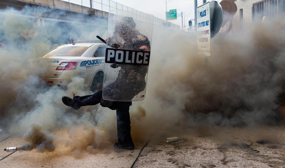 A police officer kicked a smoke canister during a Justice for George Floyd protest in downtown Miami on Saturday, May 30, 2020.