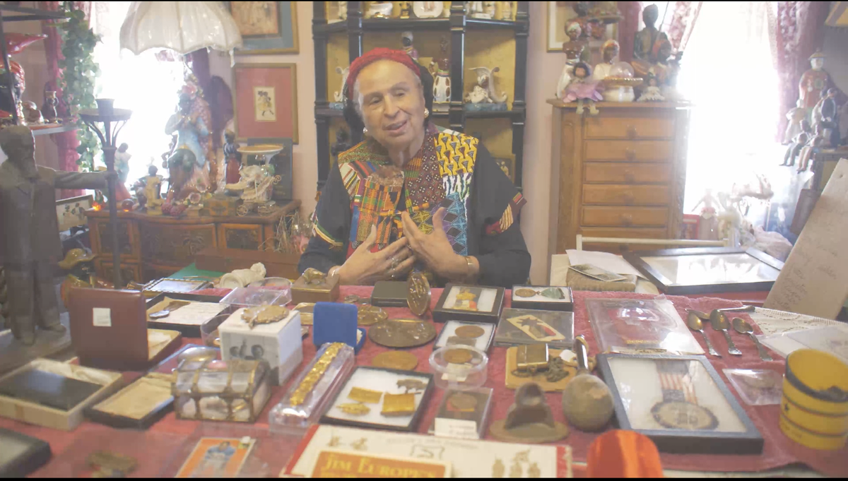 Elizabeth Meaders is selling her collection of roughly 20,000 Black history artifacts through the Guernsey’s auction house on Tuesday, March 15, 2022. Here she is seated in front of some of the items.