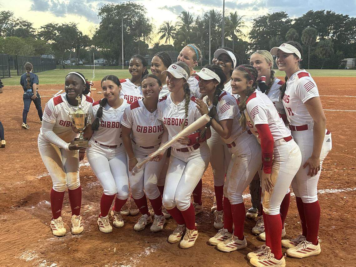 Cardinal Gibbons’ Reese Randall (holding the bat) celebrates with her teammates after they won their first BCAA Big 8 softball championship on Wednesday night at Pompano Four Fields Park.