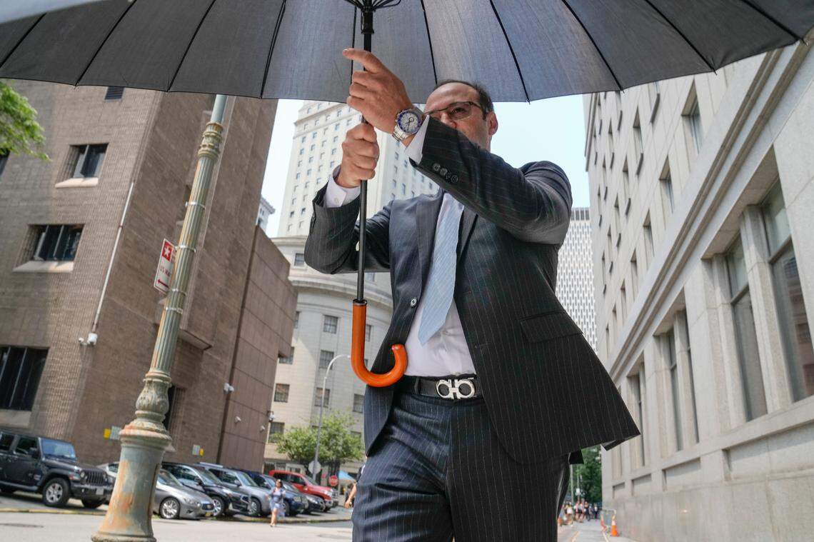 Michael Shvartsman, hides from photojournalists using an umbrella after exiting Federal Court, Thursday, July 20, 2023, in New York. (AP Photo/John Minchillo)