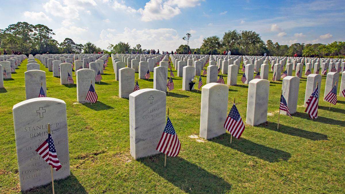 American flags stand alongside headstones of members of the military at the South Florida National Cemetery Sunday, May 30, 2021, in Lake Worth, Florida. Volunteers will be will be placing U.S. flags on some of the 25,000 graves where members of the military are buried in preparation for a Memorial Day ceremony on Monday.