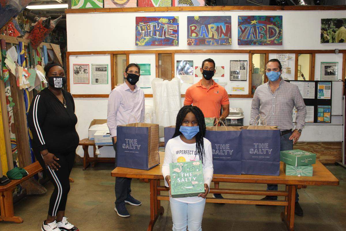 The Ransom-Everglades Alumni Can Help Too committee worked with Barnyard parent and local caterer Tiffany of TIPPS Good Eats Barnyard, left, to bring holiday meals to Coconut Grove families in need. The committee includes Carlos Dominguez, Ryan Holtzman and Kevin Grossfeld. Center is Autumn, a Barnyard student.