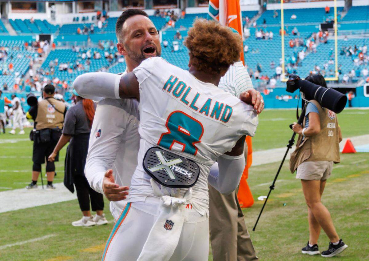 Miami Dolphins linebackers coach Anthony Campanile hugs Dolphins safety Jevon Holland (8) after the Dolphins 30-15 win over the Houston Texans during an NFL football game at Hard Rock Stadium on Sunday, November 27, 2022 in Miami Gardens, Florida.