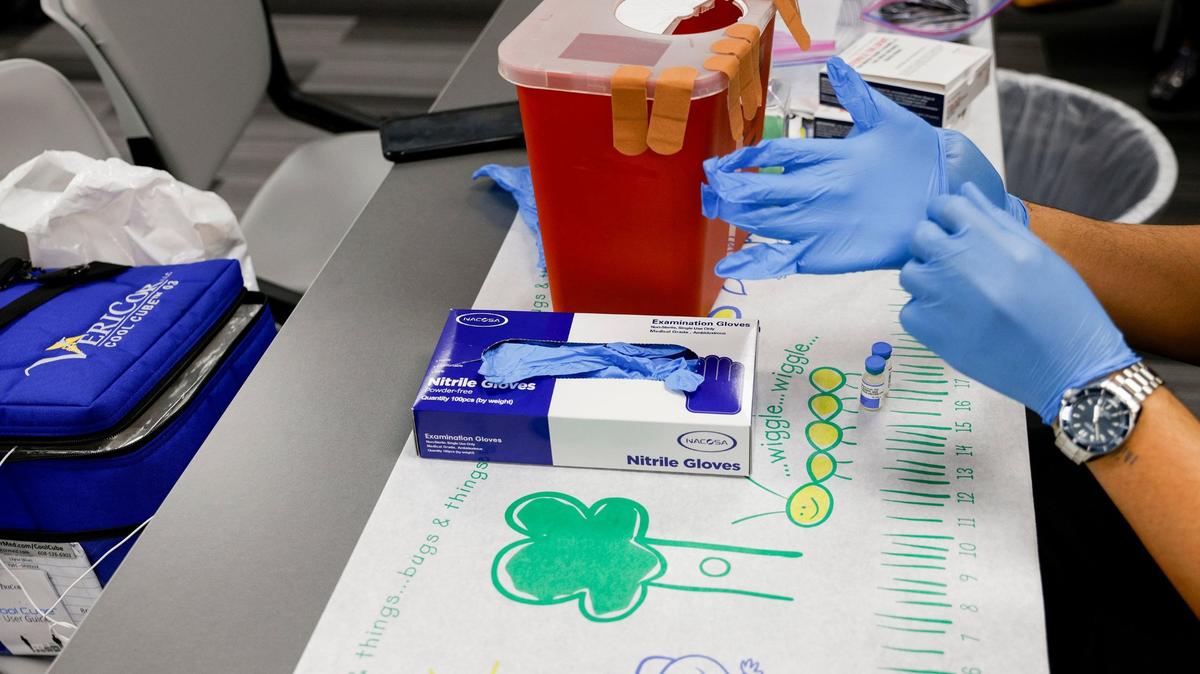 A nurse double-gloves before handling and preparing doses of the measles, mumps and rubella virus vaccine at a pop-up clinic in Carrollton, Texas, on Friday, March 7, 2025.