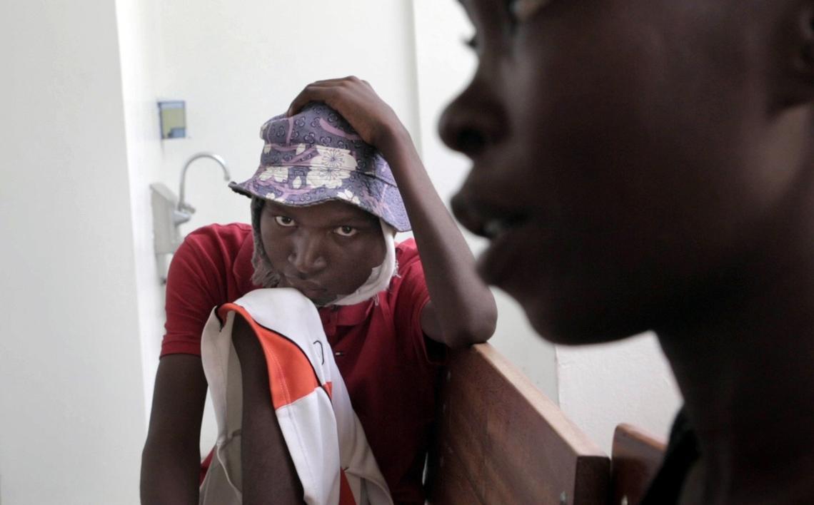 A dejected Djooly Jeune, 17, sits by his mother, Angena Altidor, after a nurse at the University Hospital of Mirebalais finally informs them that he would not be able to get his chemotherapy because of his blood work.
