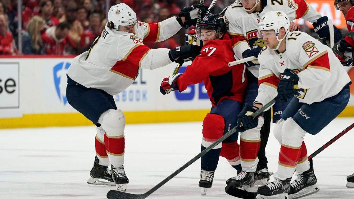 Florida Panthers defenseman Ben Chiarot, left, with centers Eetu Luostarinen (27) and Sam Reinhart (13) combine to keep the puck from Washington Capitals right wing T.J. Oshie (77) during the first period of Game 4 in the first round of the NHL Stanley Cup hockey playoffs, Monday, May 9, 2022, in Washington. (AP Photo/Alex Brandon)
