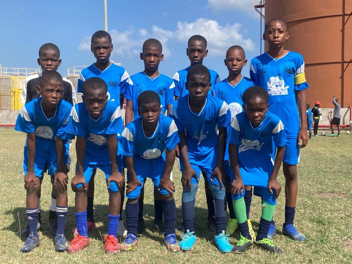 Eleven-year-old Josué St. Vilus, in black, was a goalkeeper for Olympique École de Football in Sarthe, Haiti who dreamed of one day defending the country’s red-and-blue national colors. He was killed on Saturday, May 16, 2026 when a stray bullet tore through his abdomen as his family tried to flee gang attacks.
