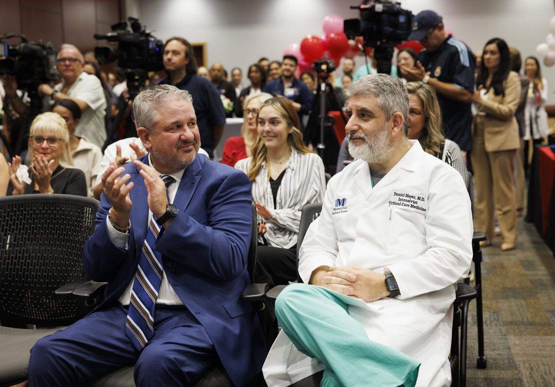 Joe Stuczynski, CEO of Memorial Hospital West, left, smiles at Dr. Daniel Mayer, Critical Care Medicine Specialist and head of Priscilla Timmons' care team, during a gathering reuniting ICU patient Priscilla Timmons with therapy dog Scrunchie and the rest of her care team on Wednesday, Oct. 22, 2025, at Memorial Hospital West in Pembroke Pines, Fla. “It gives me a reason to come back to work everyday,” said Mayer. 