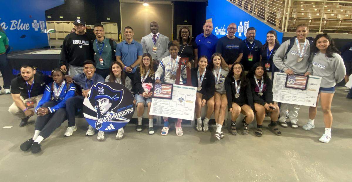 South Dade girls wrestlers and coaches gather on the medal stand with the FHSAA wrestling state runners-up trophy on Saturday at Silver Spurs Arena in Kissimmee.