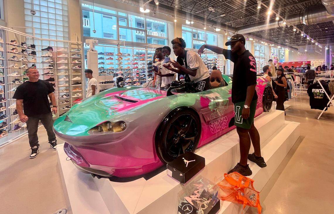 Fans pose in the watersports vehicle at the grand opening of the We The Best SNIPES store on Thursday, August 3, 2023 in Miami Beach, Florida. Complete with a recording studio, homages to Art Deco and even an Aston Martin-inspired watersports vehicle, the store aims to provide an “unique shopping experience like no other,” DJ Khaled said in a statement.