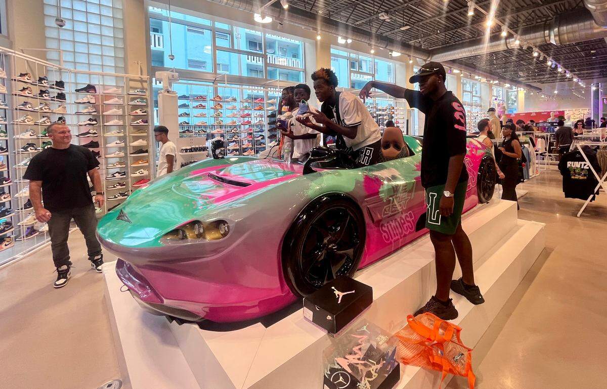 Fans pose in the watersports vehicle at the grand opening of the We The Best SNIPES store on Thursday, August 3, 2023 in Miami Beach, Florida. Complete with a recording studio, homages to Art Deco and even an Aston Martin-inspired watersports vehicle, the store aims to provide an “unique shopping experience like no other,” DJ Khaled said in a statement.
