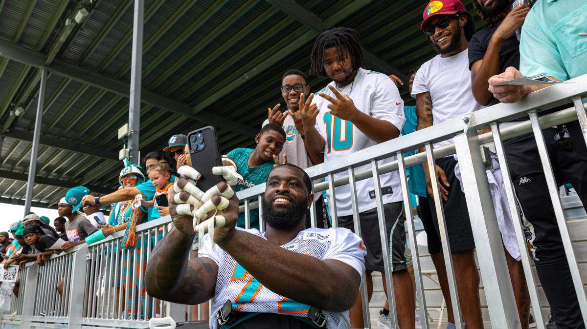 Miami Dolphins tackle Terron Armstead (72) takes a selfie with fans during Day 6 of training camp at Baptist Health Training Complex on Tuesday, July 30, 2024, in Miami Gardens, Fla.