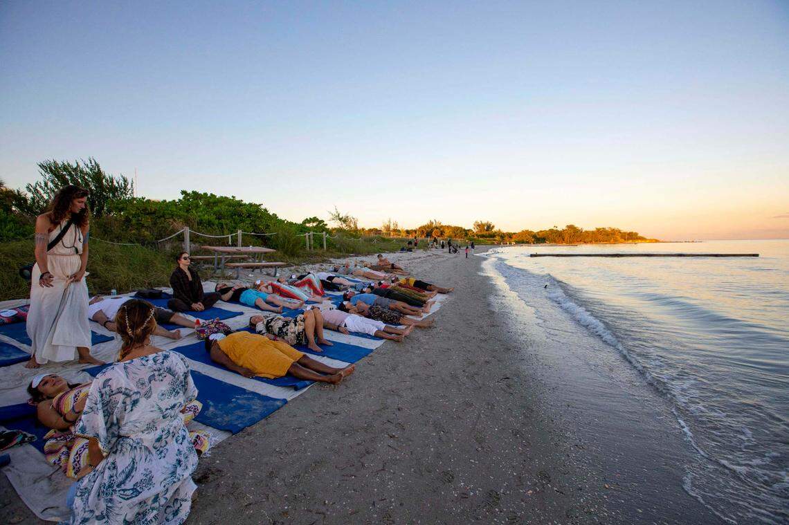 People participate in a meditation session near the water during Art With Me music and cultural festival at Historic Virginia Key Beach Park.