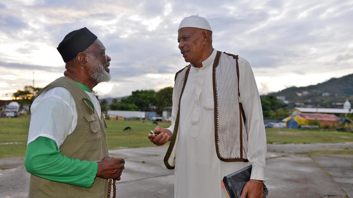 In this photo taken May 3, 2013, Yasin Abu Bakr, right, who led a small army that stormed Trinidad & Tobago’s parliament in 1990, speaks with a fellow member of his group, Jamaat al Muslimeen, at their compound in Port-of-Spain, Trinidad. Abu Bakr, never convicted of any charges, presided over a mosque and school complex in the country’s capital, and shared time among his four wives, the maximum Islam allows.