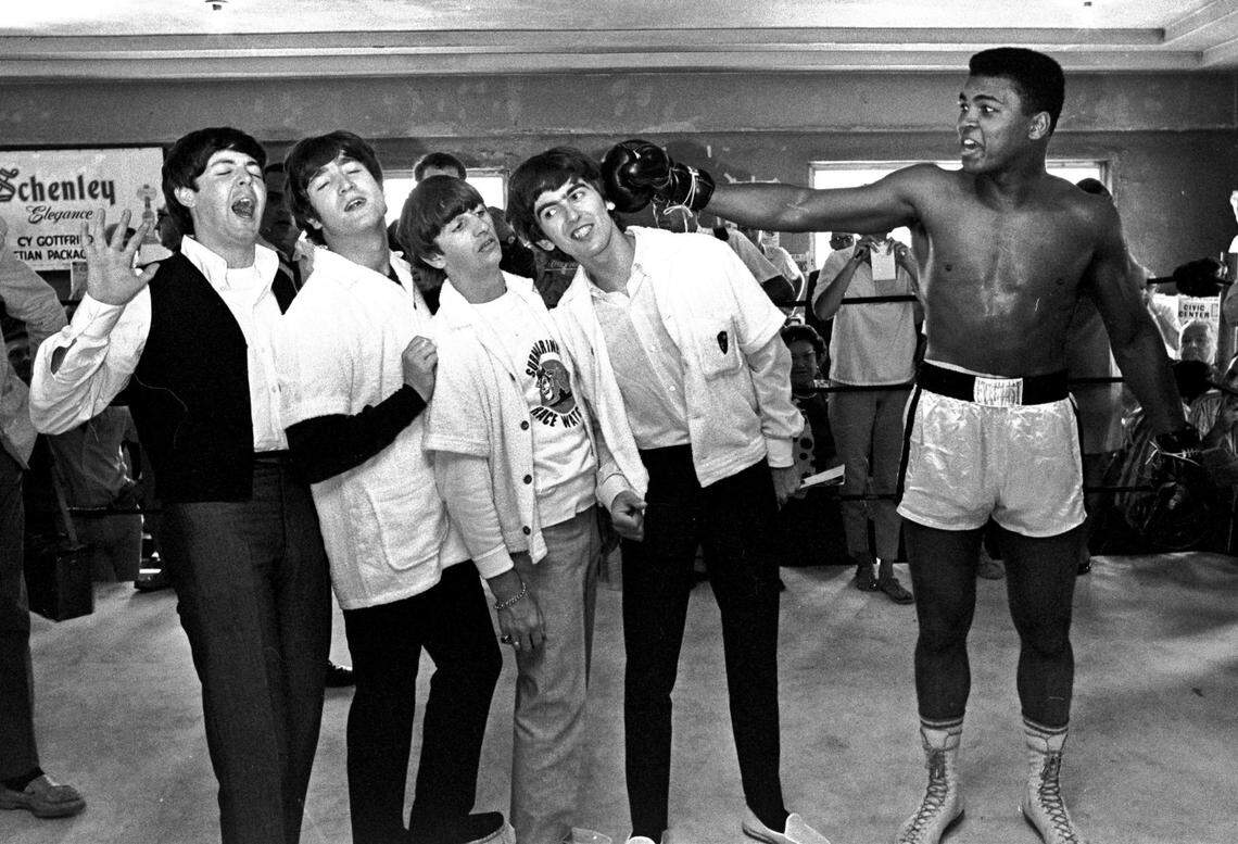 In this Feb. 18, 1964, file photo, The Beatles, from left, Paul McCartney, John Lennon, Ringo Starr, and George Harrison, take a fake blow from Cassius Clay, who later changed his name to Muhammad Ali, while visiting the heavyweight contender at his training camp in Miami Beach.