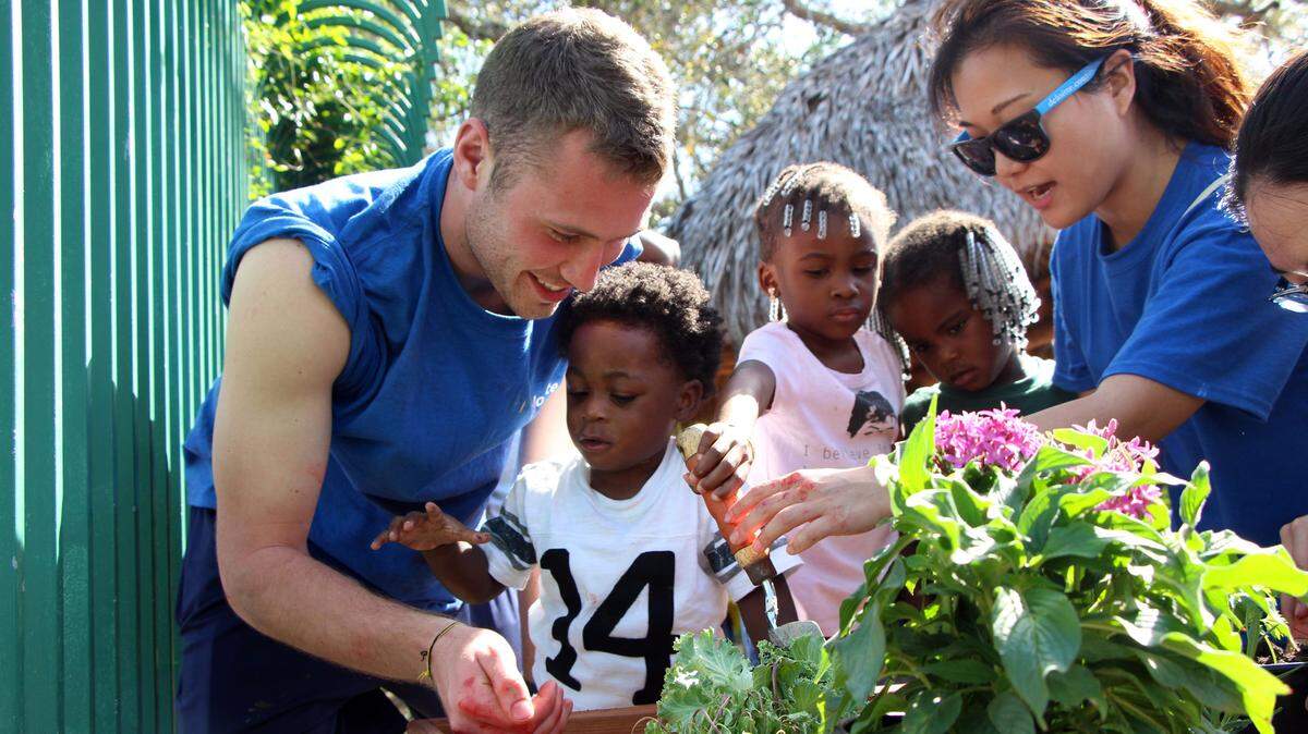 Members of the United Way Young Leaders initiiative help children with a gardening project.