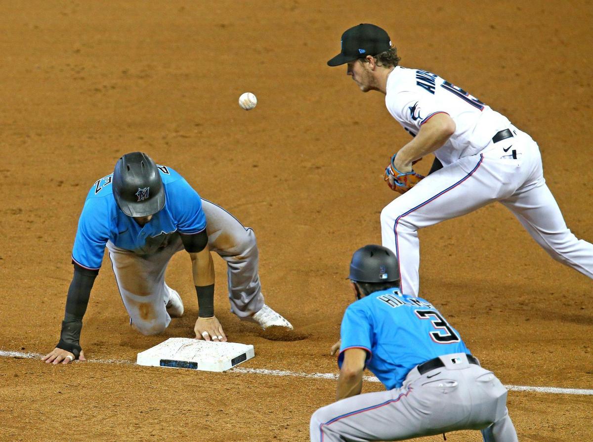 Miami Marlins Eddy Alvarez (65) slides into third base safely as Brian Anderson (15) drops the ball in a simulated game at Marlins Park in Miami, Florida, July 13, 2020.