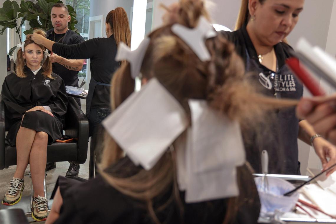 Beto Pellegrino, 41, center, hairstylist and co-owner of Elite Styles Salon & Med Spa colors the hair of client Daria Edusewicz, 32. The salon is one of the Edgewater businesses finding it hard to hire and retain employees given the rising cost of living and apartment rents in the community.