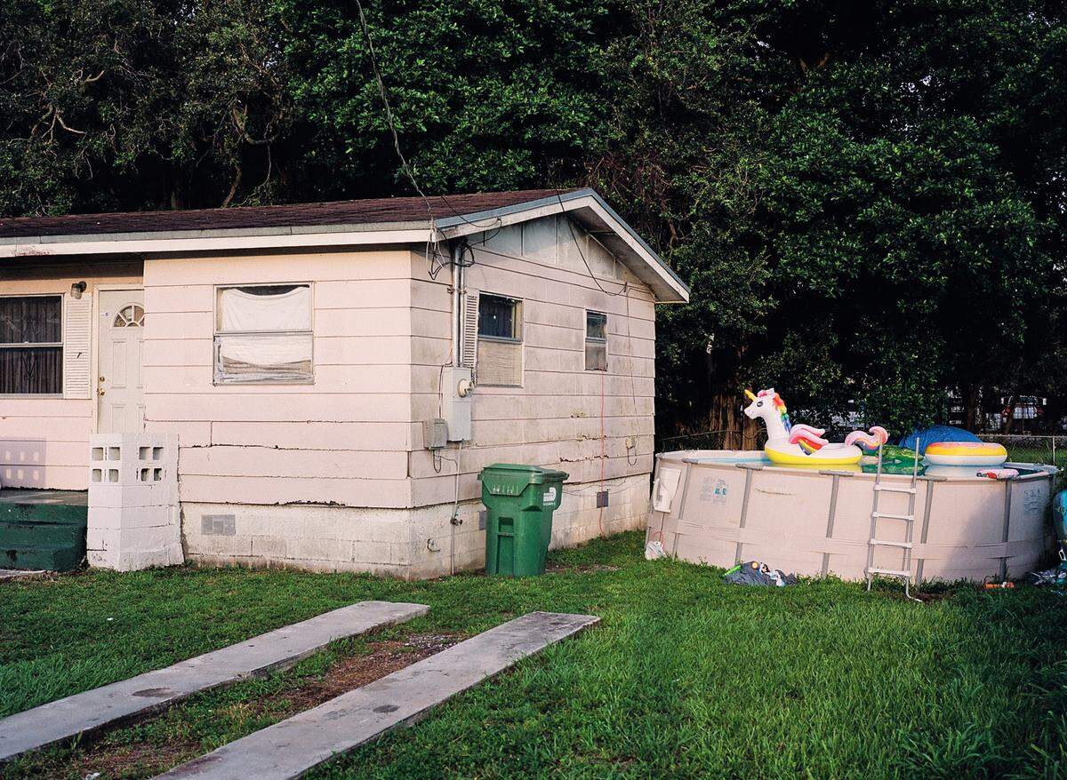 A photograph of a ranch style home with an above ground pool that contains a unicorn floaty in Brownsville. The photo will be featured in Smith Durogene’s award-winning project “Here Today, Gone Tomorrow.”