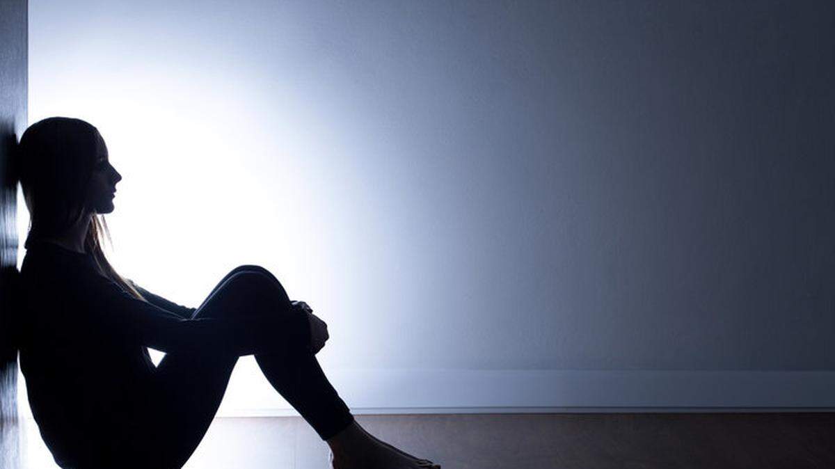 Teenager with depression sitting alone in dark room