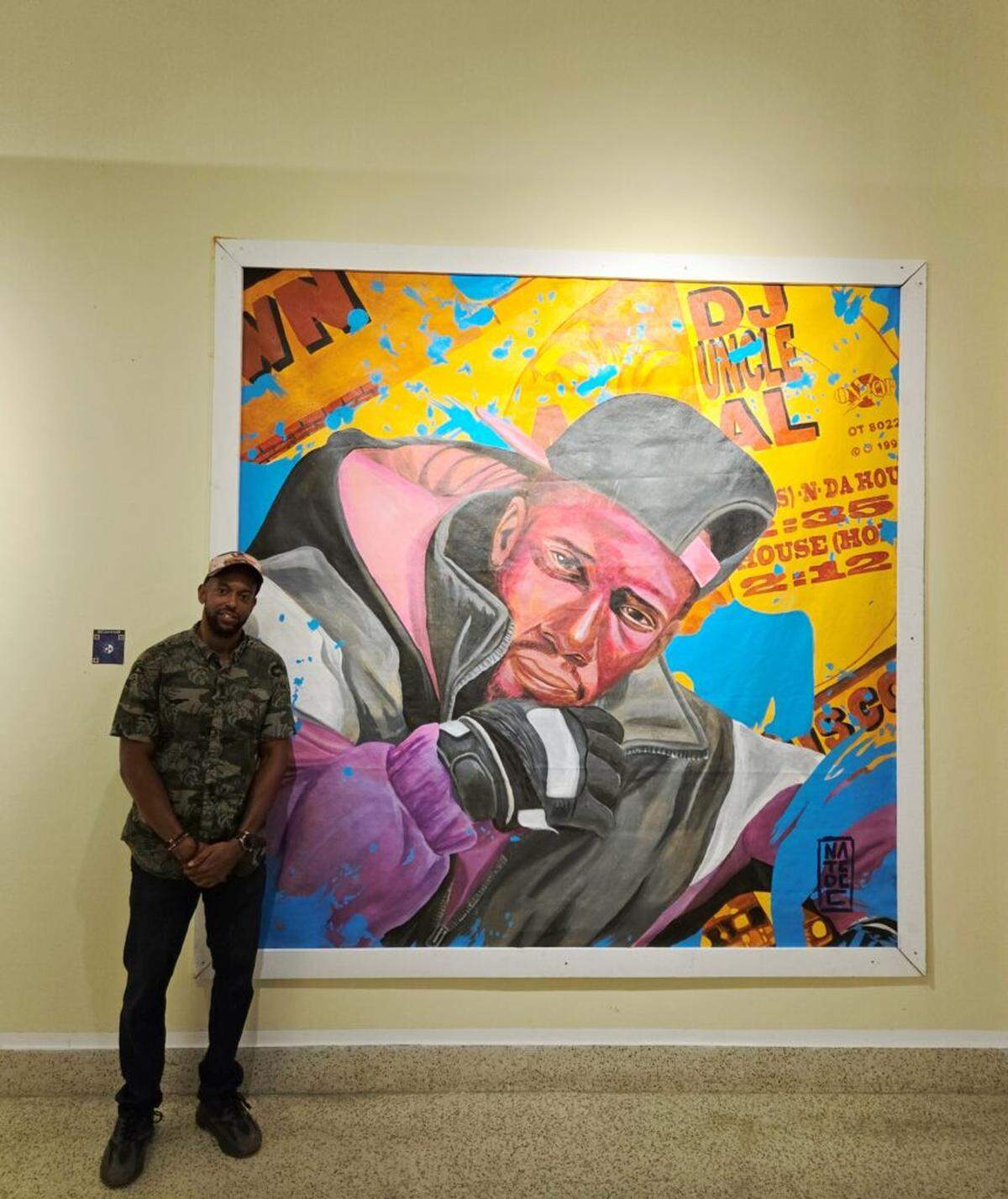 Haitian American muralist Nate Dee next to his artwork is an homage to Uncle Al (Albert Leroy Moss), an African American DJ and community leader whose legacy helped bridge cultural gaps between Haitians and African Americans.
