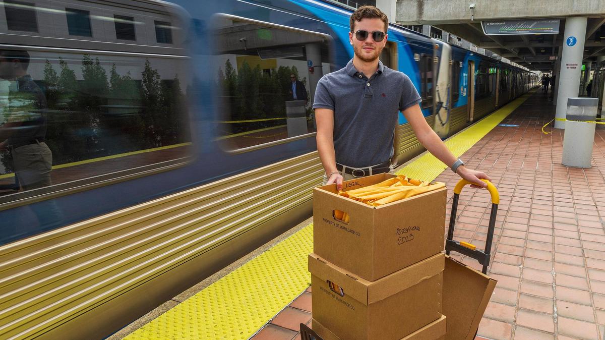 Transit advocate Kevin Amézaga poses at the Overtown Metrorail station platform with boxes full of Metrorail’s public records he got from the Miami-Dade County as he tries to unearth why Metrorail can be so late sometimes, in Miami, on Friday October 27, 2023.