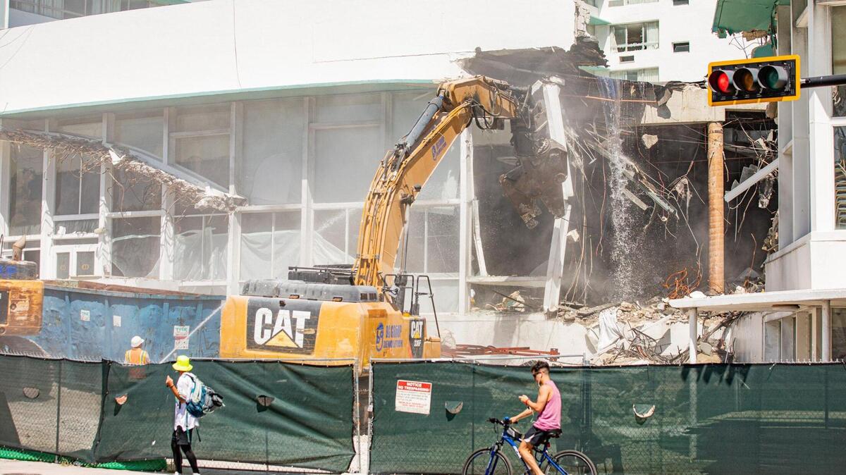 La gente patina y camina por Collins Avenue mientras comienza la demolición del Deauville Beach Resort en Miami Beach el 6 de septiembre de 2022.