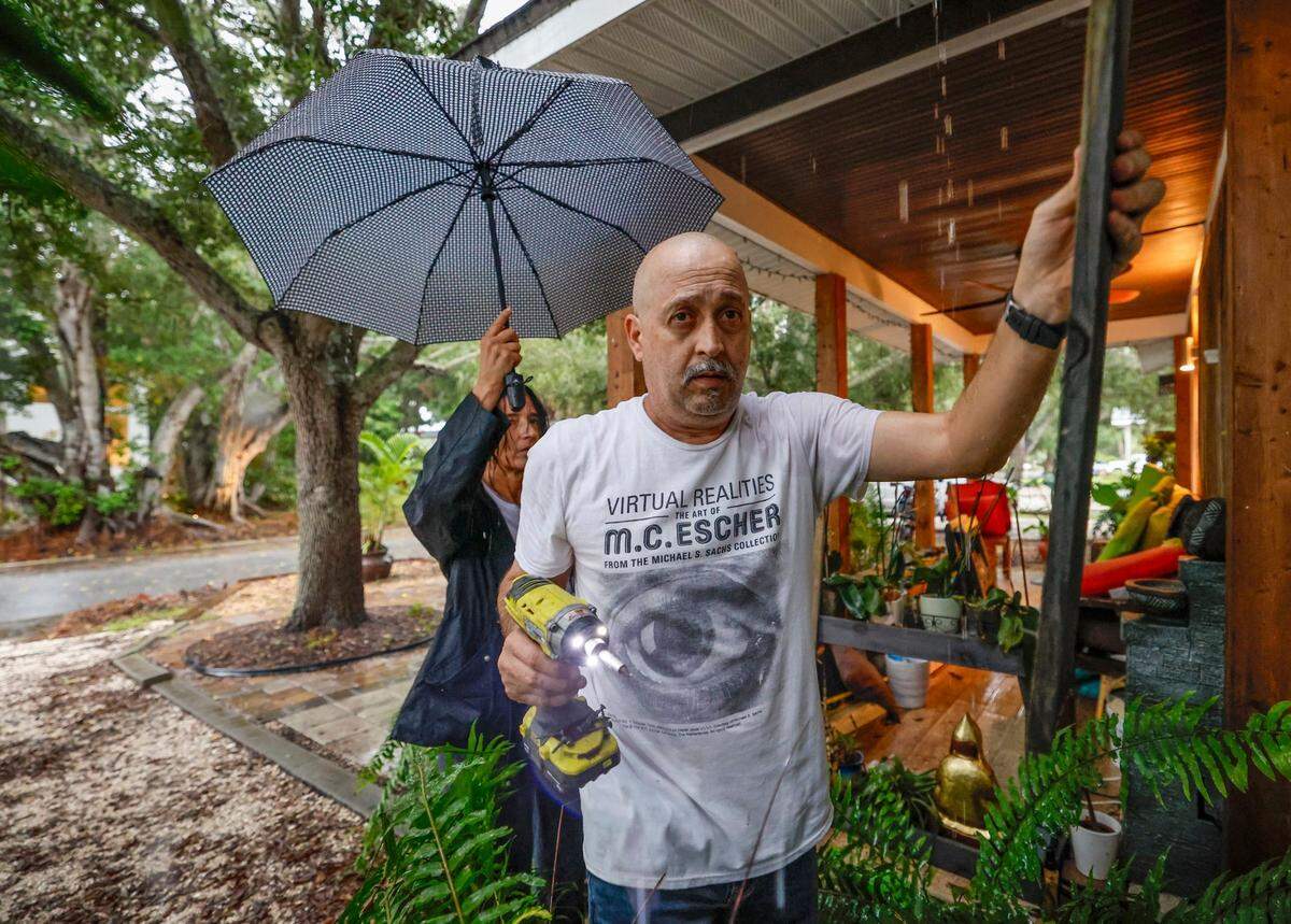 Artist Javier Dubrocq, wearing a t-shirt with an eye, and his wife Isabel Dubrocg prepare to board up their home before evacuating from Sarasota, Florida on Wednesday, October 9, 2024.