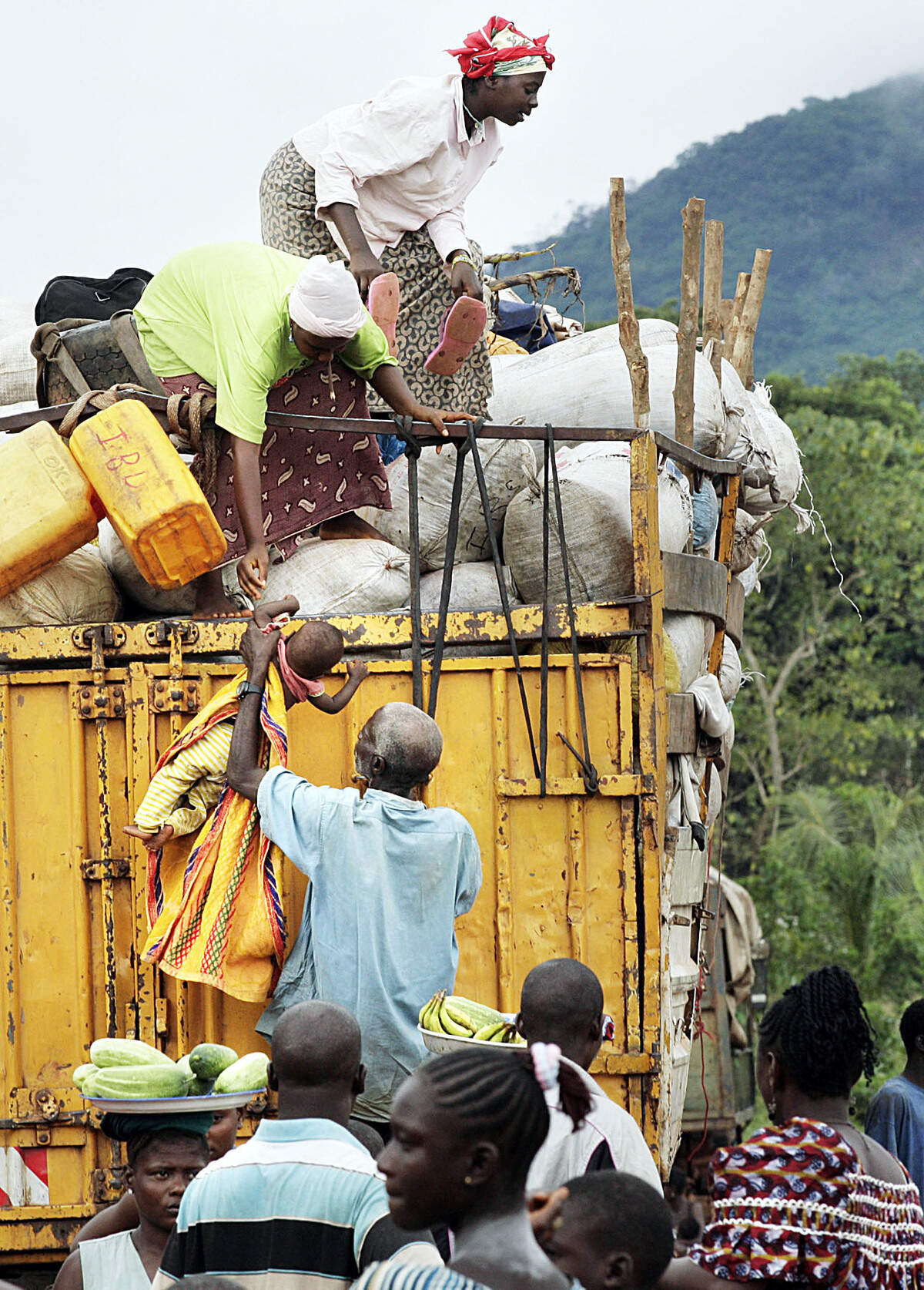 08/16/06--Christopher Herwig/For The Miami Herald--Sierra Leone, August 3, 2006, Road Trip to Bo.Baby being lowered from the top of a truck loaded with cargo and passengers ontop. Moyamba Junction. For Leonard Pitts Story. ONE TIME USE ONLY.