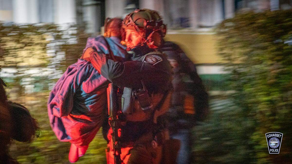 A detective bringing one of the children away from the home where they were held hostage, police said.