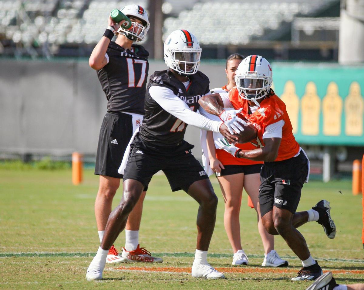 Miami Hurricanes quarterback Jacurri Brown (11) hands the ball of to running back Henry Parrish, Jr. (21) runs through practice drills at the University of Miami’s Greentree Field on Tuesday, March 7, 2023.