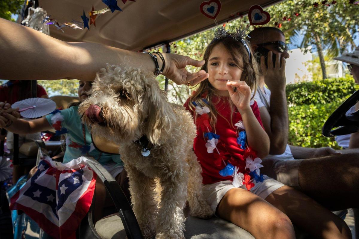 Olivia Capurro and her dog, Brownie, help get the Girl Scout troop ready before the Fourth of July parade along Crandon Boulevard in Key Biscayne.