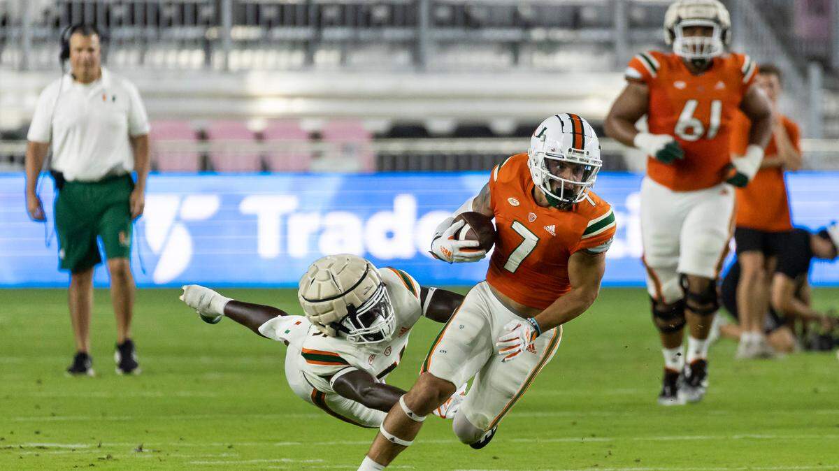 Miami Hurricanes wide receiver Xavier Restrepo (7) runs with the ball as Miami Hurricanes linebacker Wesley Bissainthe (31) tries to tackle during the first quarter of their spring game at DRV PNK Stadium on Friday, April 14, 2023, in Fort Lauderdale, Fla.