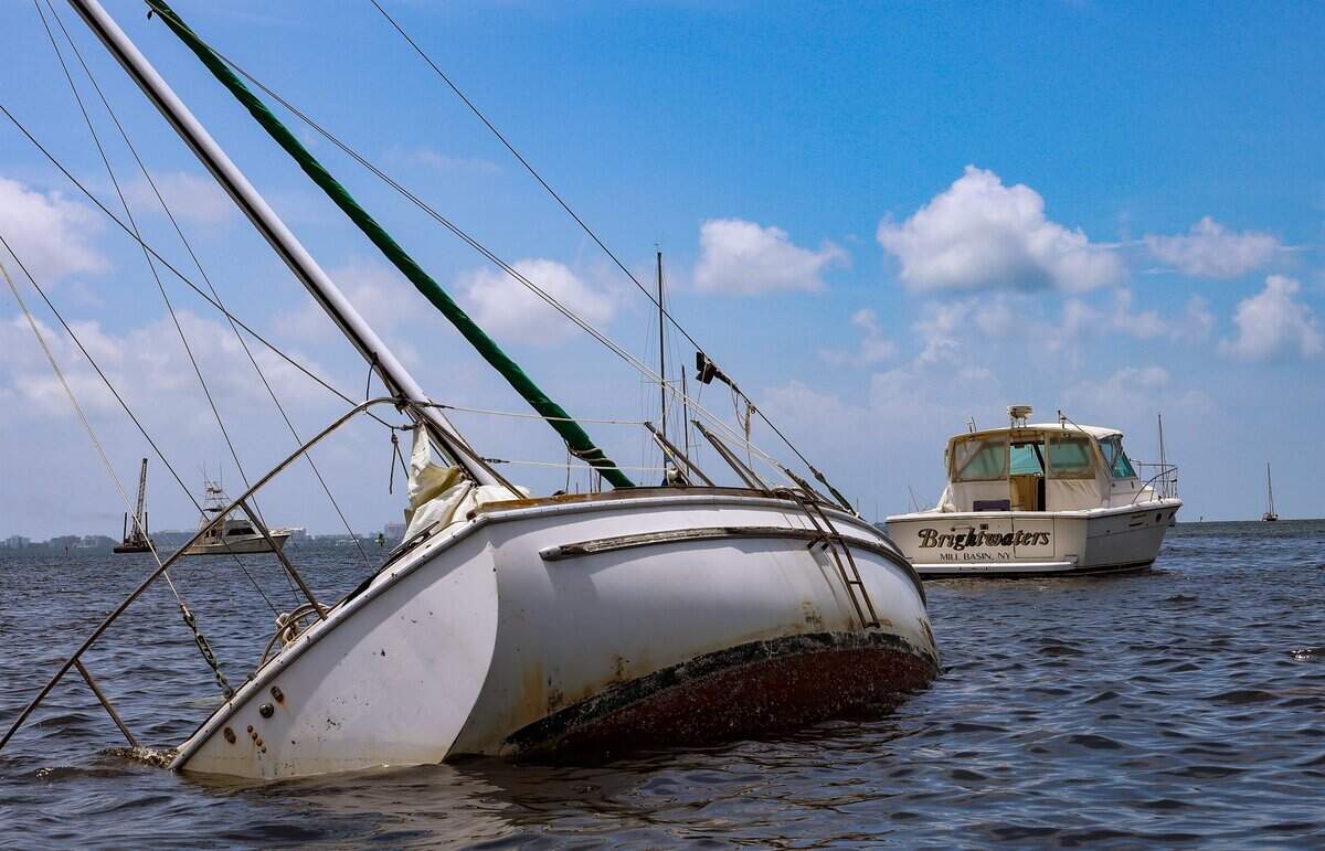 Un barco abandonado está semisumergido y volcado de lado y permanece estacionado entre otras embarcaciones en Dinner Key Marina en Coconut Grove el jueves 18 de junio de 2026, en Miami. La embarcación abandonada subraya las preocupaciones en curso sobre la falta de amarres y boyas para satisfacer la demanda.