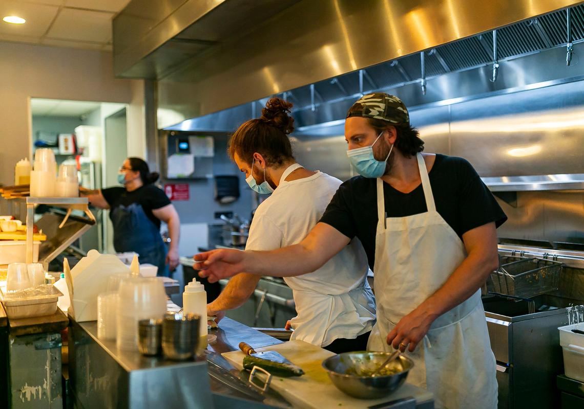 Chefs Ashley Knowles, Evan Colosi, 26, and Tim Piazza, 34, prepare food at the Ghee Indian Kitchen. Tight quarters and a speedy kitchen means sometimes line cooks can stay at least three feet apart. Other times not.