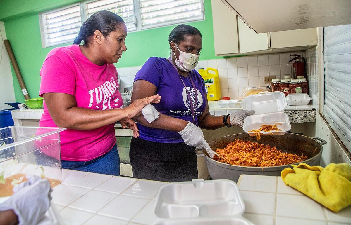 Maria Villegas, left, and Judith Edward prepare food to give away to people in Loíza, Puerto Rico, on Wednesday.