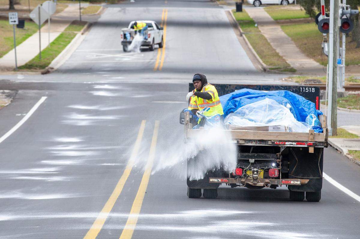 Jacob Rimmey spreads salt on the road along E. Blount Street as crews prepare for expected snow in the Pensacola area on Tuesday, Jan, 21, 2025.
