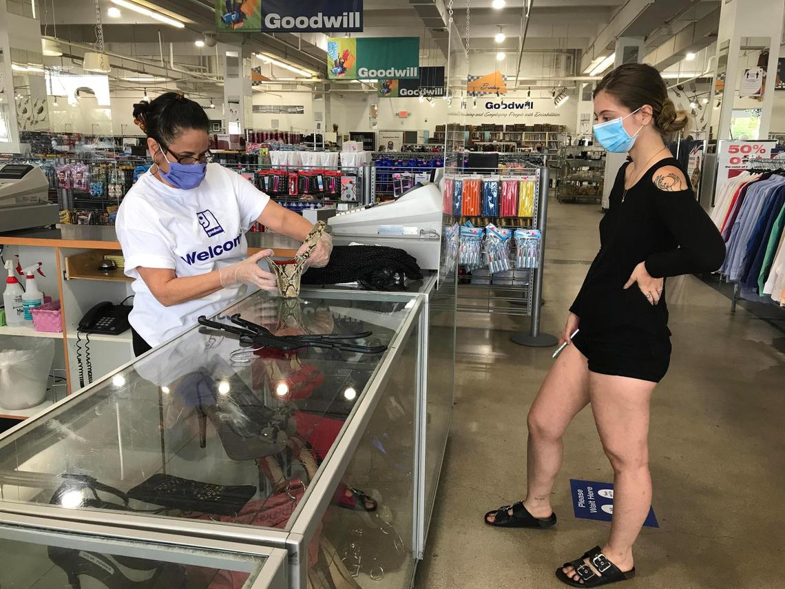 Miami, Florida, May 18, 2020- Shopper Cristina Garzon (right) waits at the checkout counter as Cashier Caridad Alonso checks the price on the merchandise during the first day of reopening of non-essential stores in Miami-Dade County at the Goodwill Bird Ludlam store, 6842 SW 40th St, Miami, FL 33155,