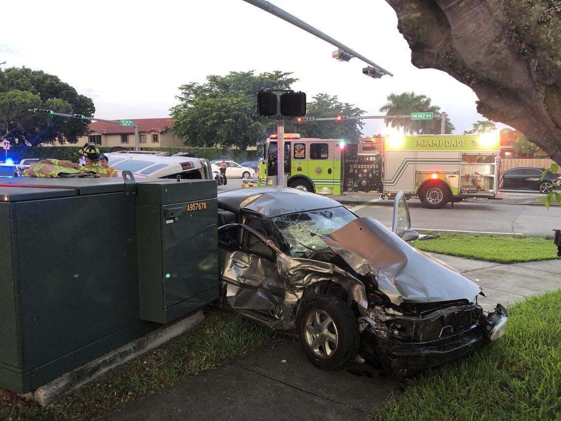 A dark-colored car is badly mangled on the sidewalk following a crash with a private school bus Friday morning.