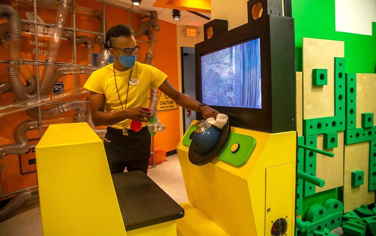 Staff member John Settles sanitizes an interactive play station at the Miami Children’s Museum on Tuesday, April 27, 2021.