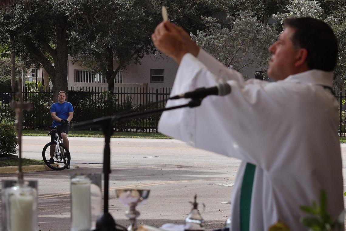 A bike rider attends Father Alberto Cutié’s parking lot service at St. Benedict’s Episcopal Church. Houses of worship are adapting in various ways to the pandemic.