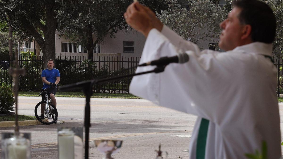 A bike rider attends Father Alberto Cutié’s parking lot service at St. Benedict’s Episcopal Church. Houses of worship are adapting in various ways to the pandemic.
