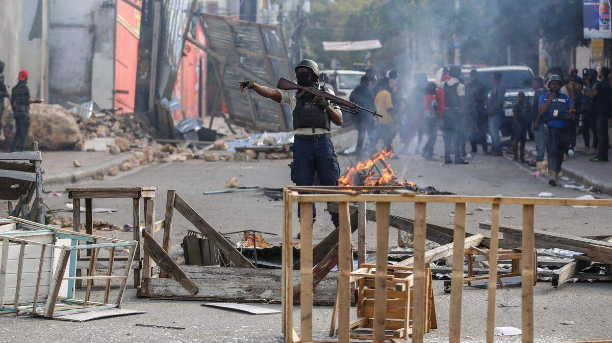 Police secure a roadblock set up by protesters during a demonstration demanding the resignation of Prime Minister Ariel Henry, in Port-au-Prince, Haiti, Wednesday, Feb. 7, 2024. (AP Photo/Odelyn Joseph)