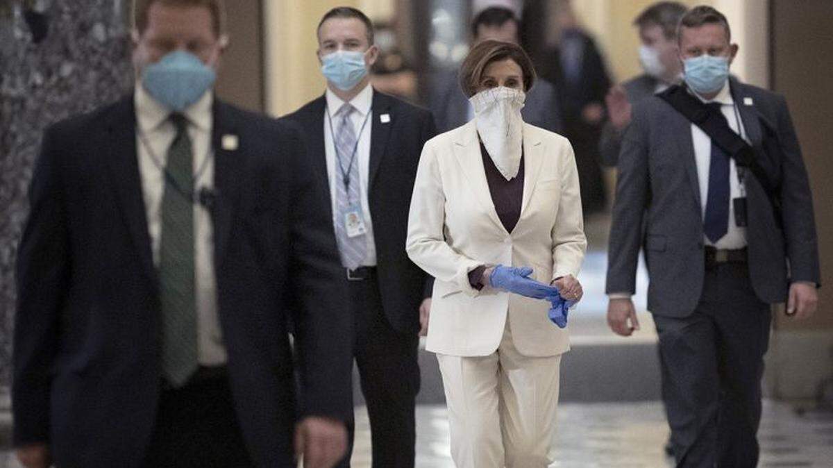 U.S. House Speaker Nancy Pelosi removes a pair of rubber gloves while returning to her office after the start of a vote on the April 23 stimulus package.